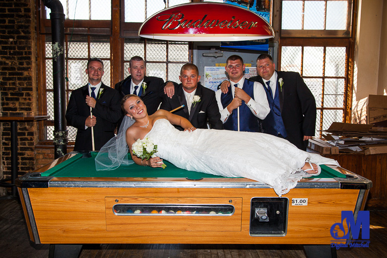 bride on pool table with groomsmen